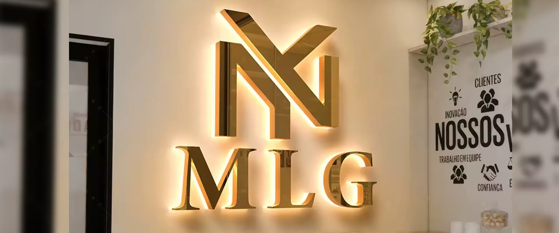 Logotipo dorado iluminado de MLG en pared de oficina