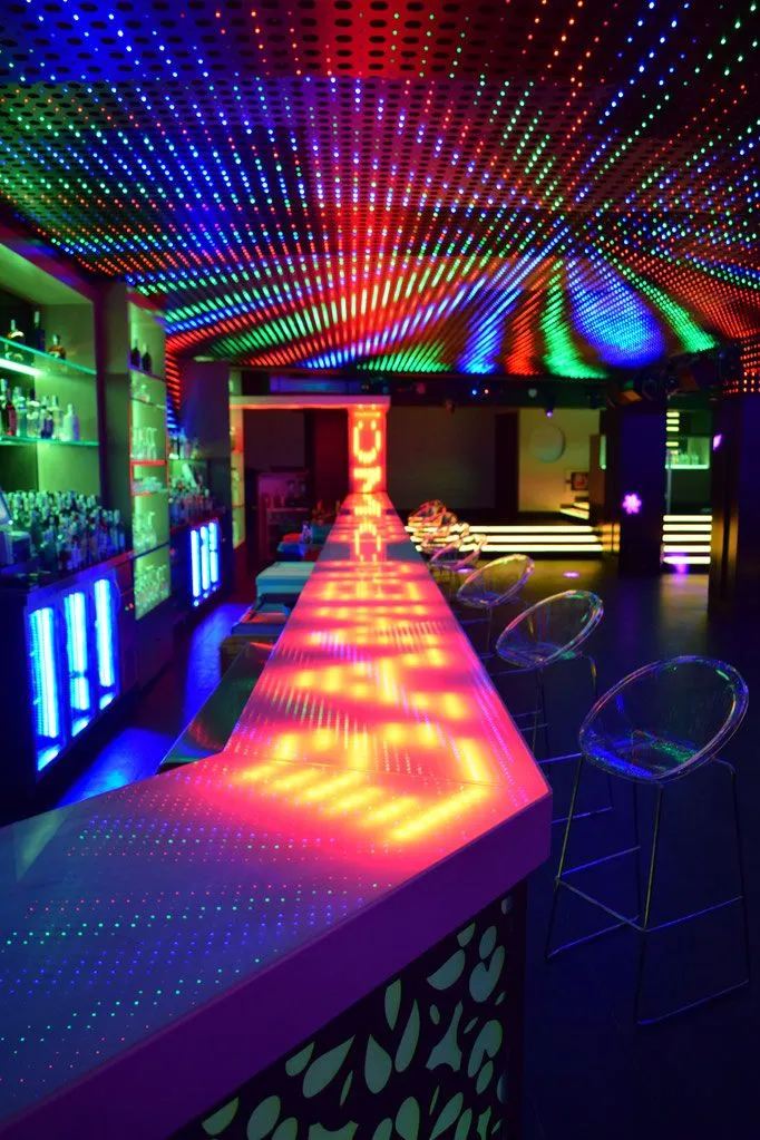 Barra de discoteca iluminada con luces pixel LED multicolor en techo y superficies