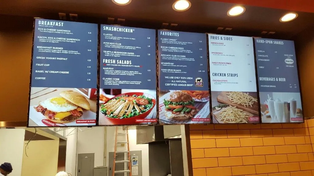 Pantallas digitales de menú con desayuno, hamburguesas y acompañamientos en restaurante de comida rápida