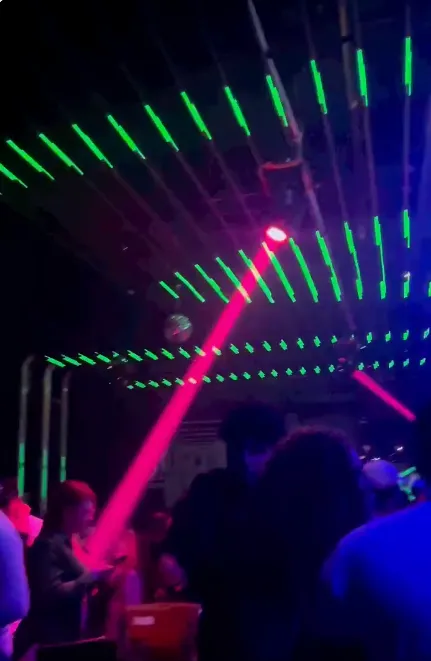 Club nocturno con techo de tiras pixel LED verdes y luces láser rojas durante fiesta