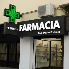 Letrero color verde con letras acrílicas blancas con el nombre de FARMACIA en mayúsculas y un símbolo de cruz verde luminosa.