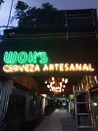 Letrero neón de Wok's Cerveza Artesanal en colores verde y ámbar de noche